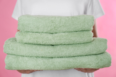 Woman holding fresh towels on pink background, closeup