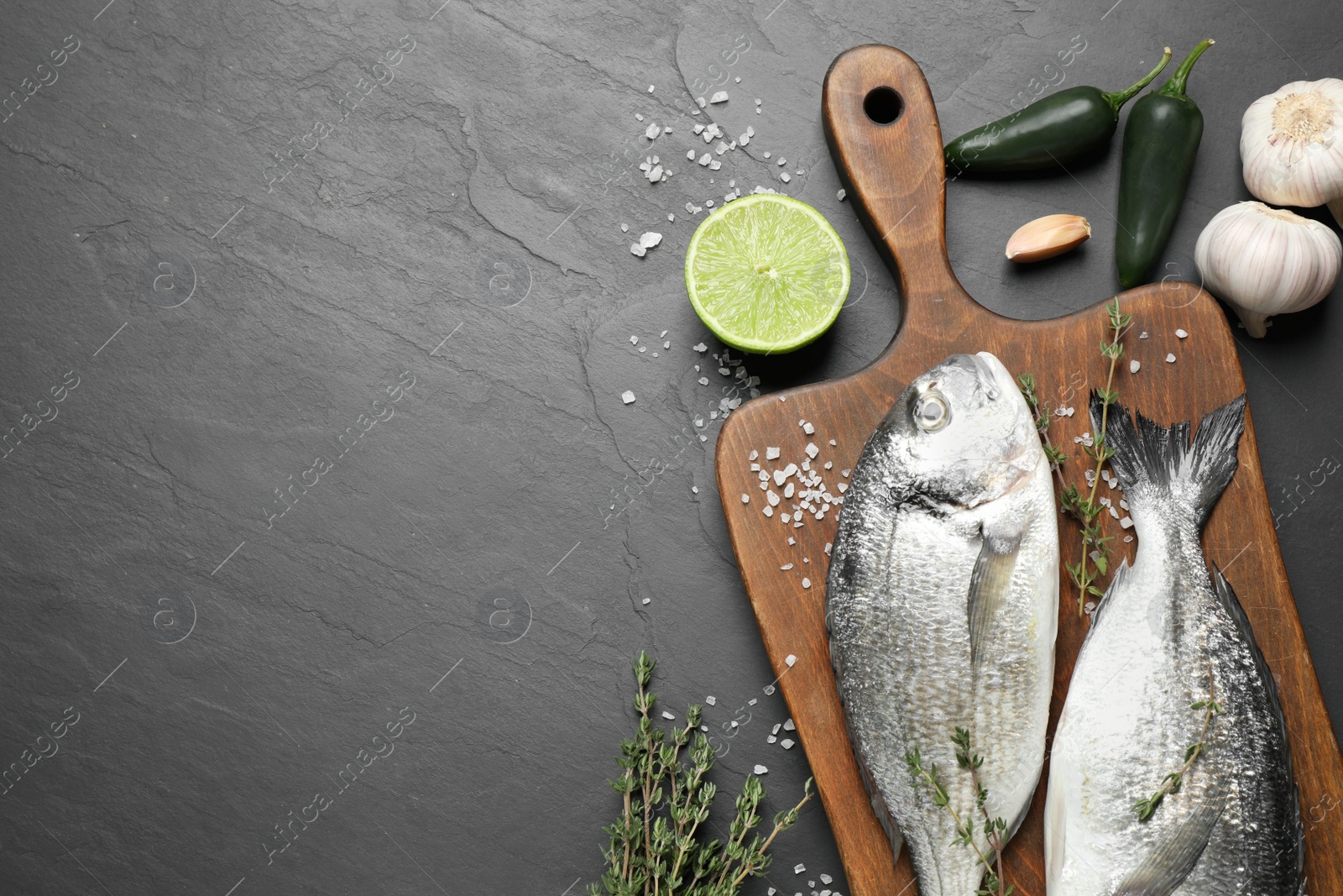 Photo of Flat lay composition with raw dorada fish on black table, space for text