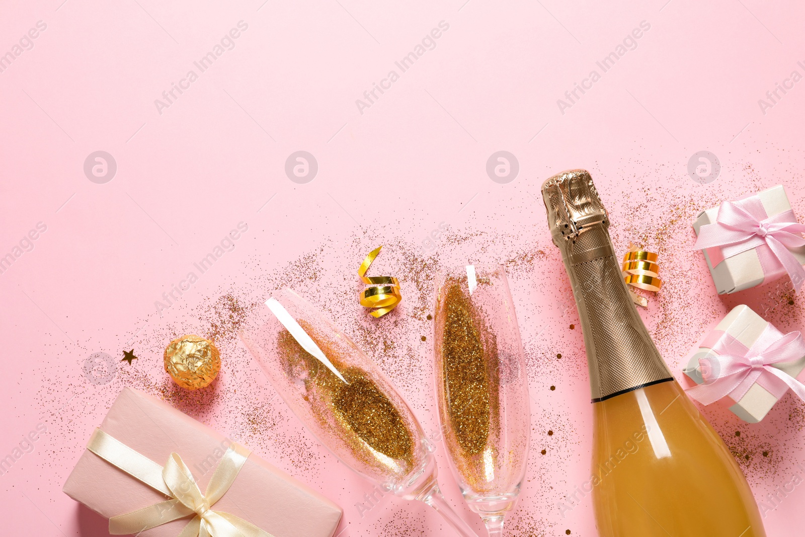 Photo of Flat lay composition with bottle of champagne for celebration on pink background. Space for text