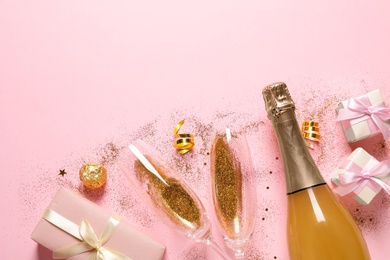 Flat lay composition with bottle of champagne for celebration on pink background. Space for text