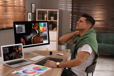 Photo of Tired retoucher at workplace with computer and laptop in office