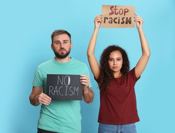 Photo of Young man and African American woman holding signs on turquoise background. Racism concept
