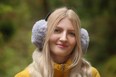 Photo of Young beautiful woman wearing warm earmuffs outdoors