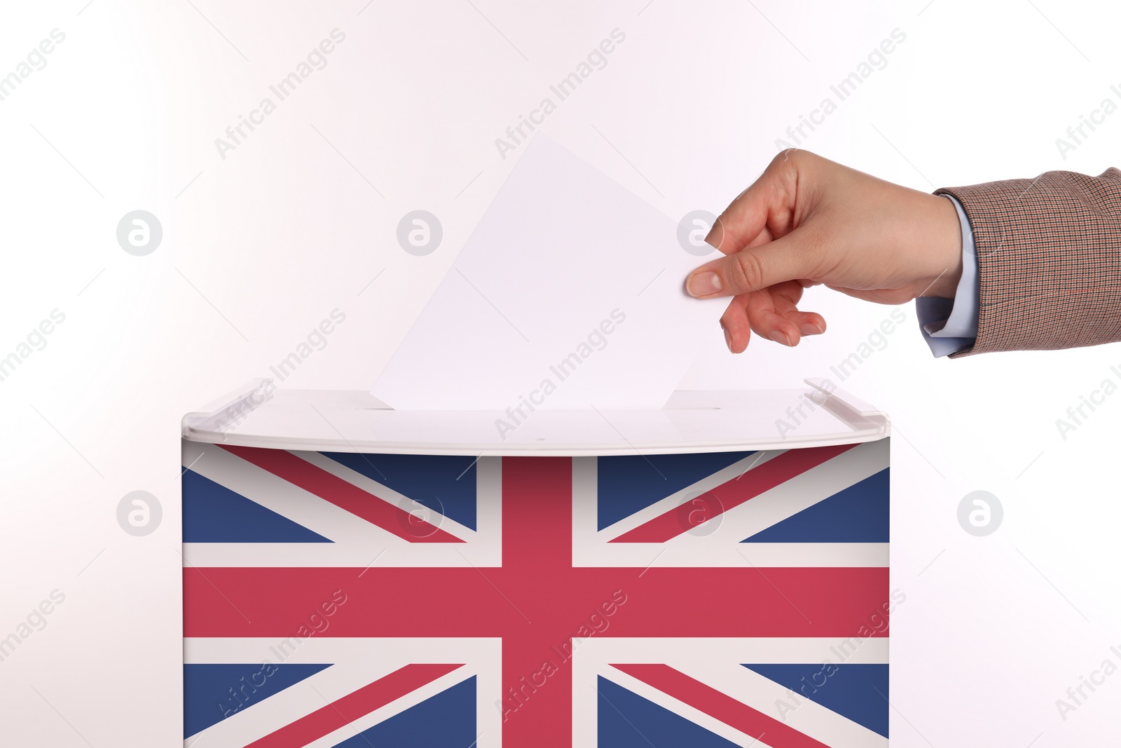Image of Woman putting her vote into ballot box decorated with flag of United Kingdom against white background, closeup