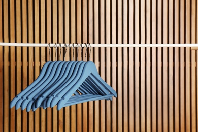 Photo of Empty hangers on rail against wooden background, space for text
