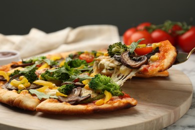 Photo of Taking piece of delicious vegetarian pizza at table, closeup