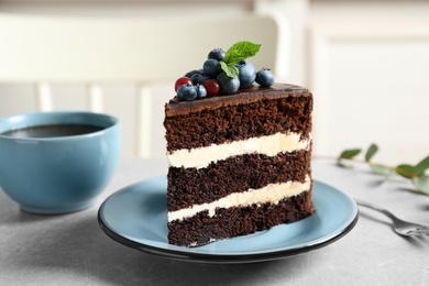 Plate with slice of chocolate sponge berry cake on grey table