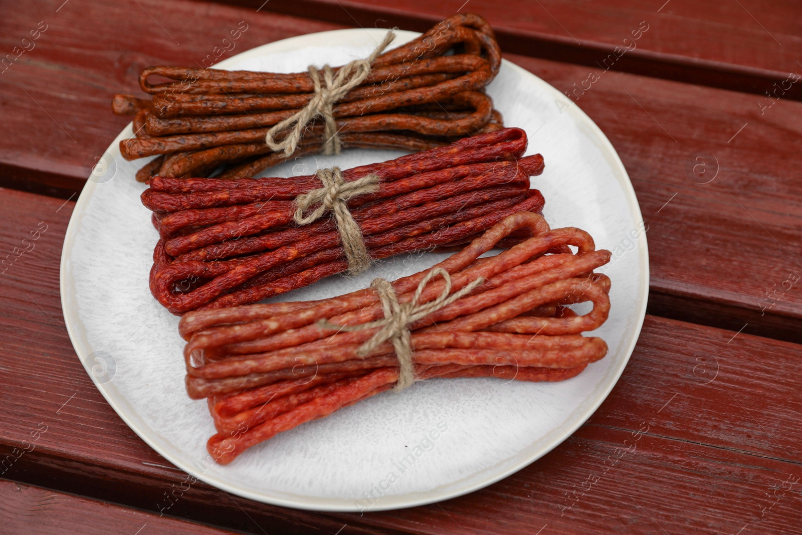 Photo of Bundles of delicious kabanosy on wooden table