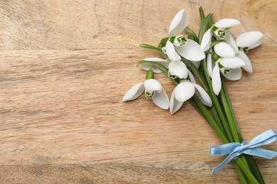 Photo of Beautiful snowdrops on wooden table, top view. Space for text