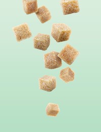 Image of Brown cane sugar cubes falling on turquoise gradient background