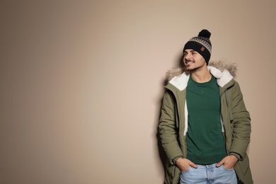 Young man wearing warm clothes on color background, space for text. Ready for winter vacation