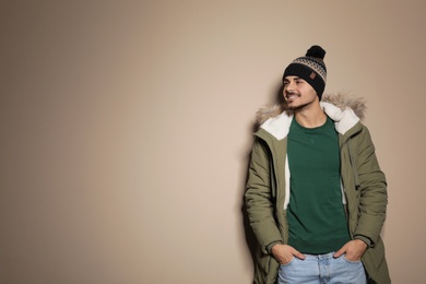 Photo of Young man wearing warm clothes on color background, space for text. Ready for winter vacation