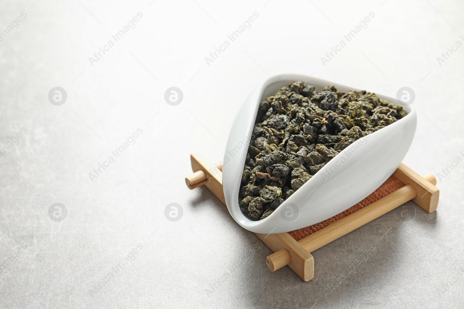 Photo of Chahe of Tie Guan Yin oolong tea leaves on light background. Space for text