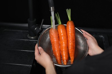 Photo of Woman washing fresh ripe juicy carrots under tap water in sink, closeup