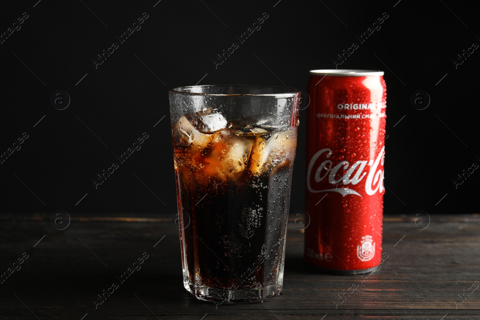 Photo of MYKOLAIV, UKRAINE - NOVEMBER 15, 2018: Glass and can with Coca Cola on table against black background