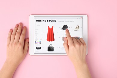 Photo of Woman with tablet shopping online on pink background, top view