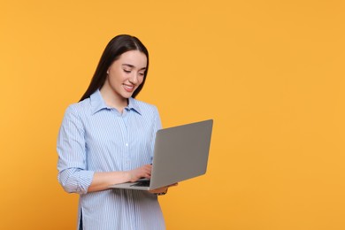 Photo of Smiling young woman working with laptop on yellow background, space for text