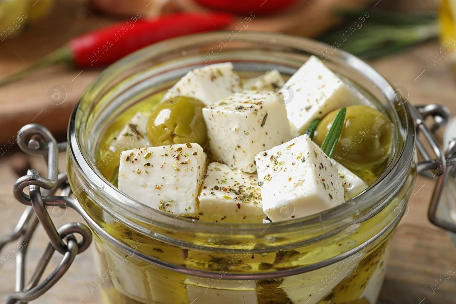 Photo of Pickled feta cheese in jar on wooden table, closeup