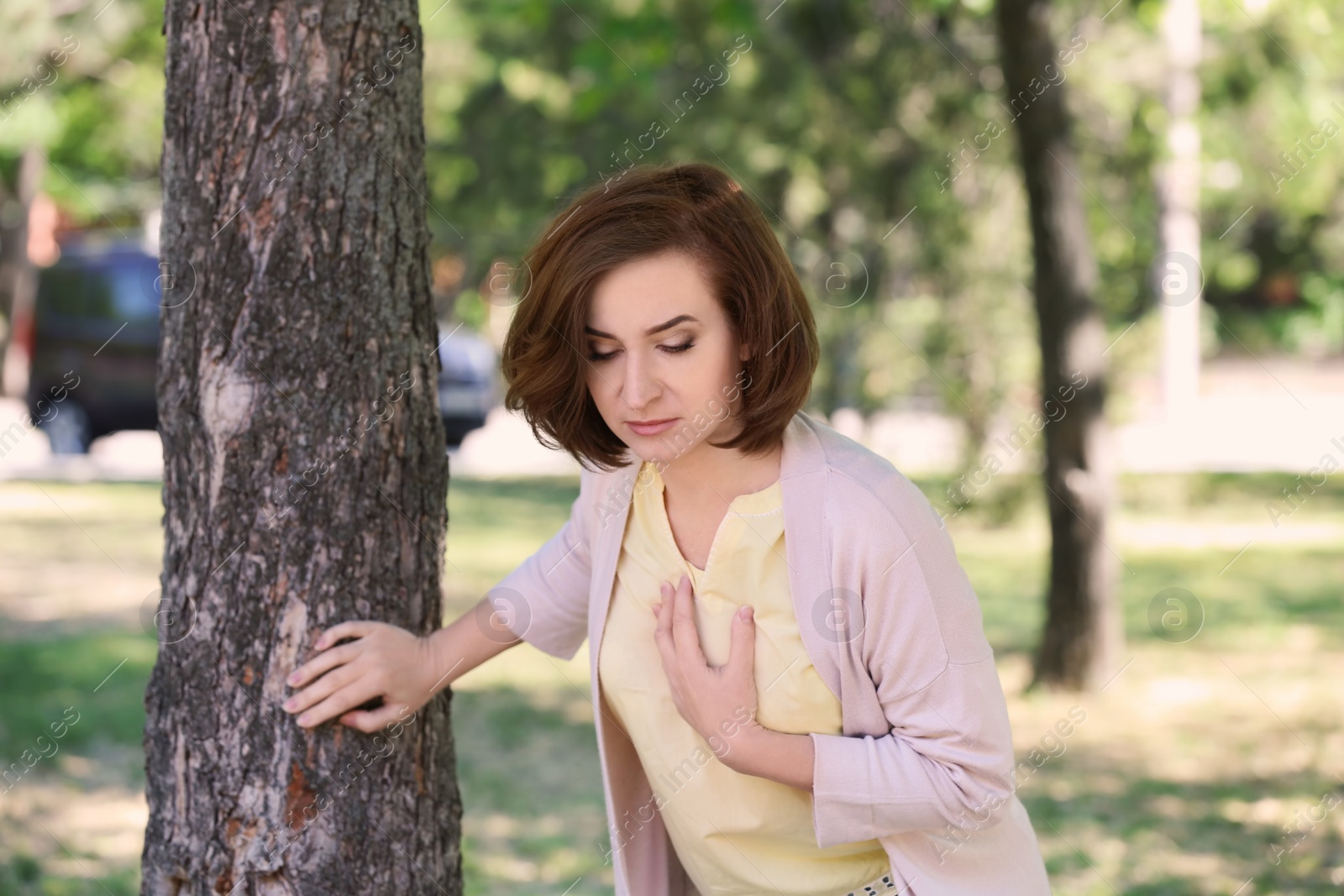 Photo of Mature woman having heart attack near tree in park