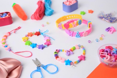 Photo of Kid's handmade beaded jewelry and different supplies on color background