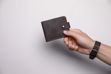 Photo of Man holding leather wallet on light background, closeup. Space for text