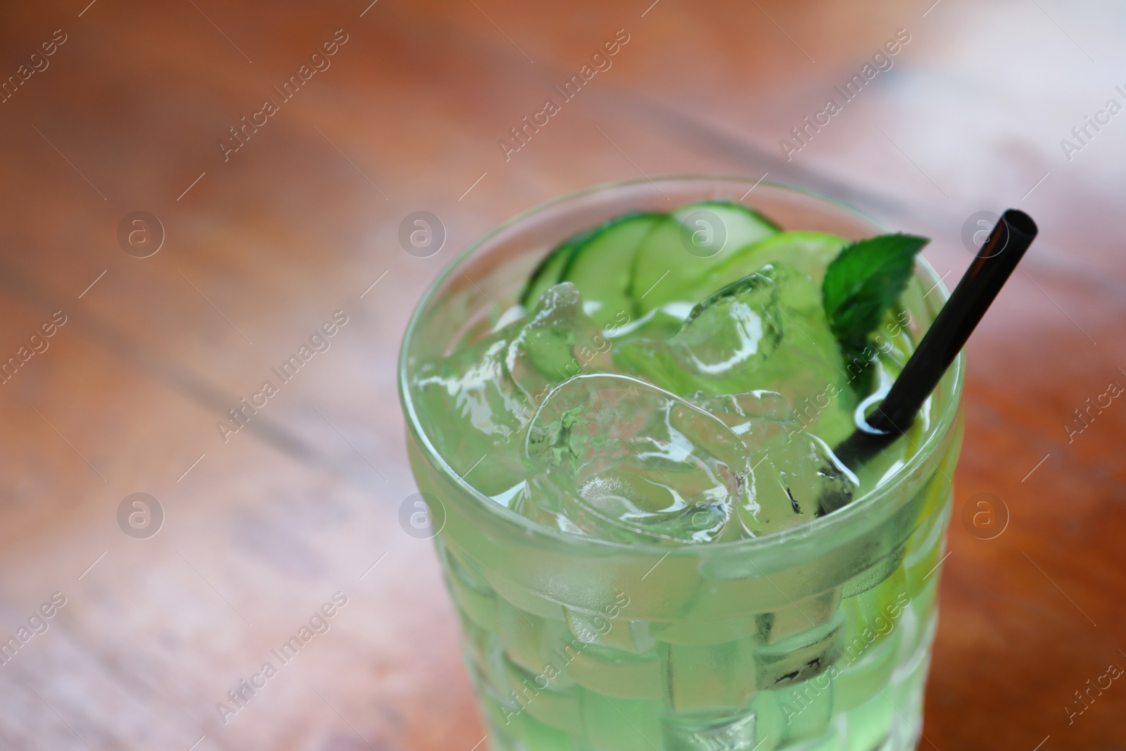 Photo of Glass of delicious cocktail with ice on table, closeup