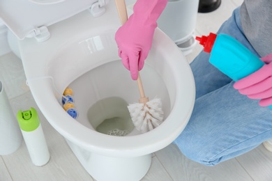 Photo of Woman cleaning toilet bowl in bathroom