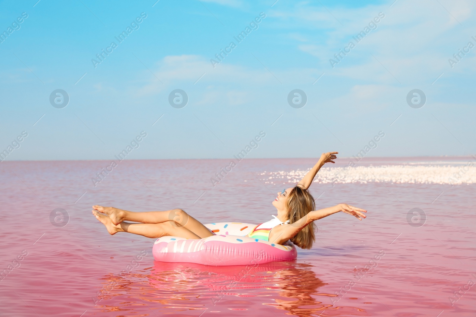 Photo of Beautiful woman on inflatable ring in pink lake