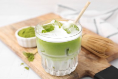 Glass of tasty iced matcha latte on wooden board, closeup