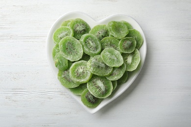 Photo of Plate with slices of kiwi on wooden background, top view. Dried fruit as healthy food