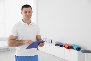 Photo of Portrait of professional physiotherapist with clipboard in rehabilitation center. Space for text