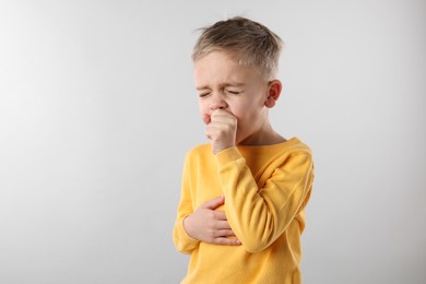 Sick boy coughing on gray background. Cold symptoms
