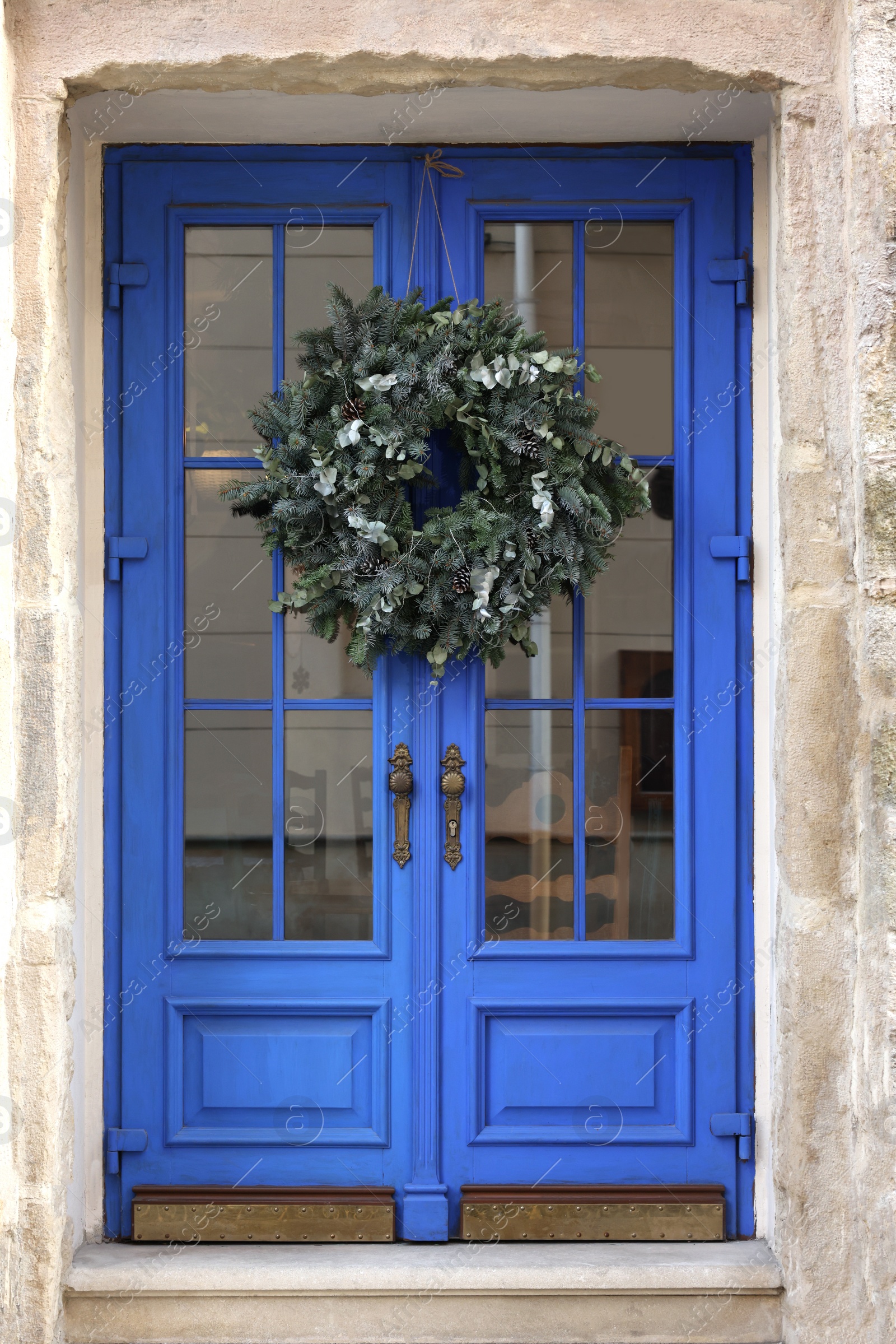 Photo of Beautiful Christmas wreath hanging on blue glass door