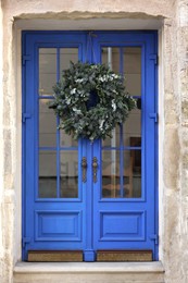 Photo of Beautiful Christmas wreath hanging on blue glass door