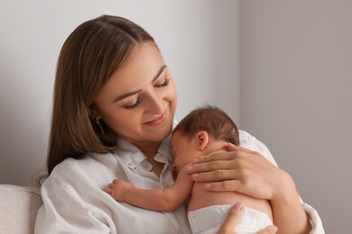 Mother holding her cute newborn baby indoors