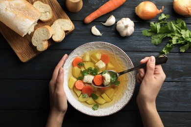 Photo of Woman eating fresh homemade chicken soup at table, top view