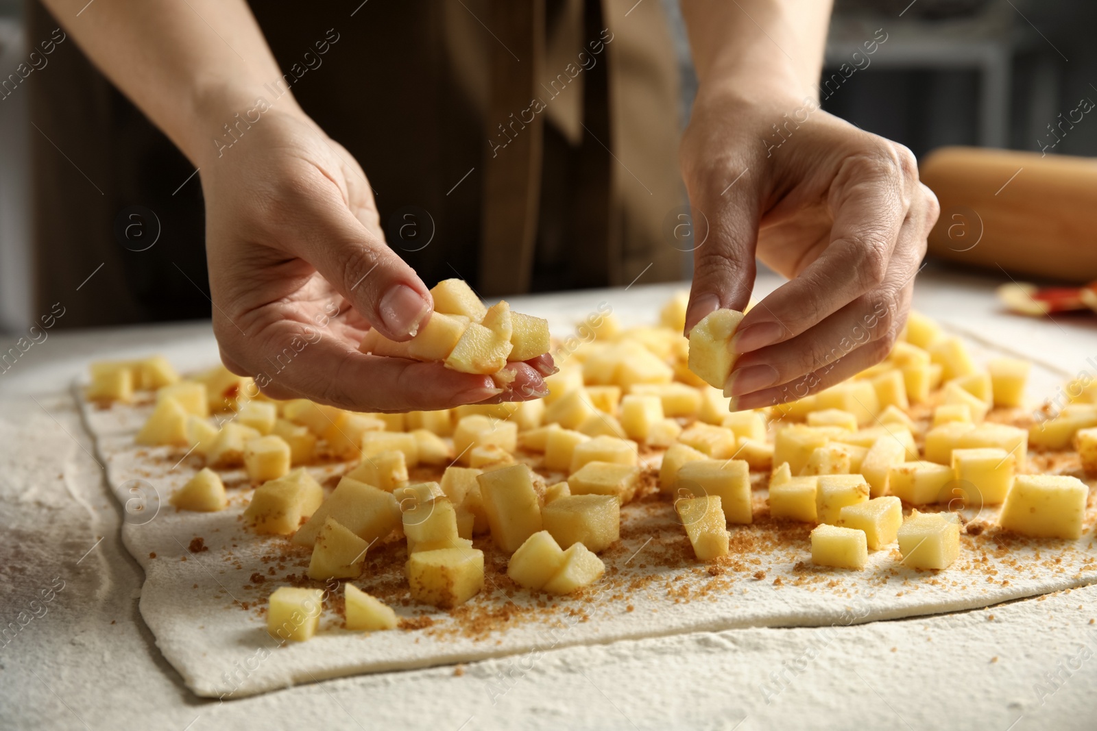 Photo of Woman making delicious apple strudel at table, closeup