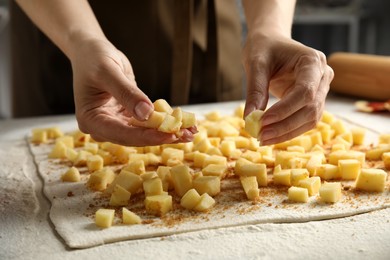 Woman making delicious apple strudel at table, closeup