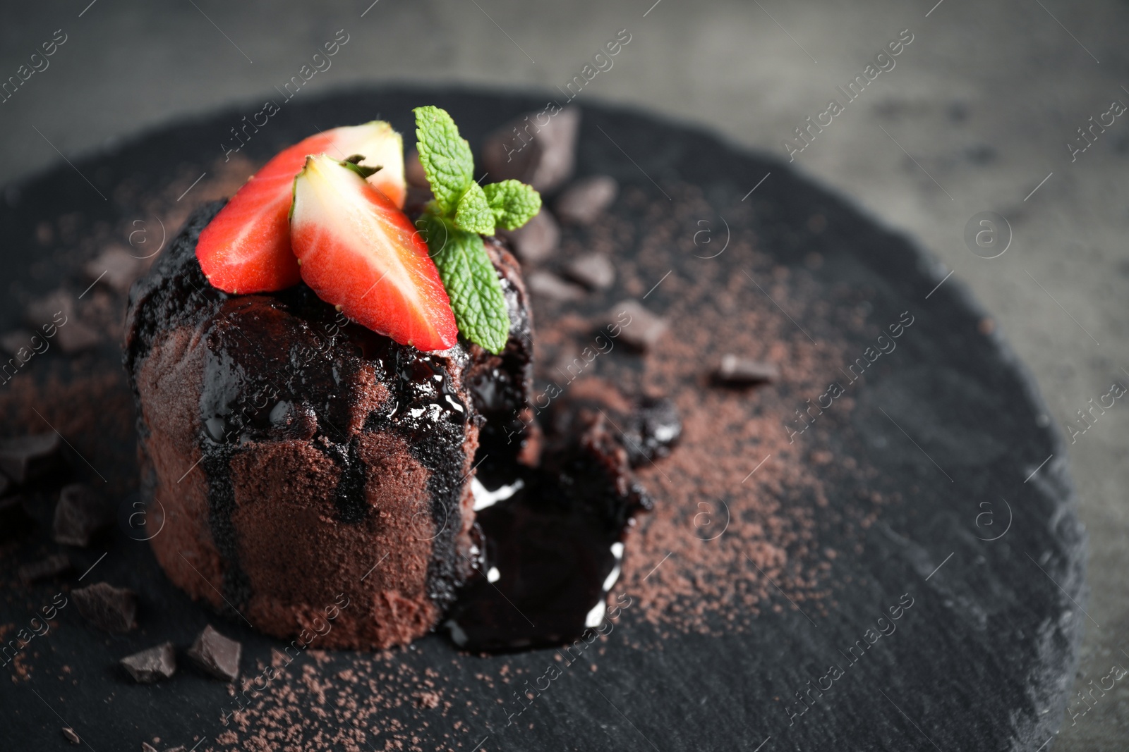 Photo of Delicious warm chocolate lava cake on slate board, closeup