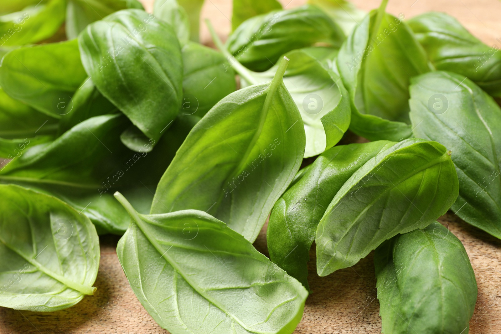 Photo of Fresh basil leaves on wooden table, closeup