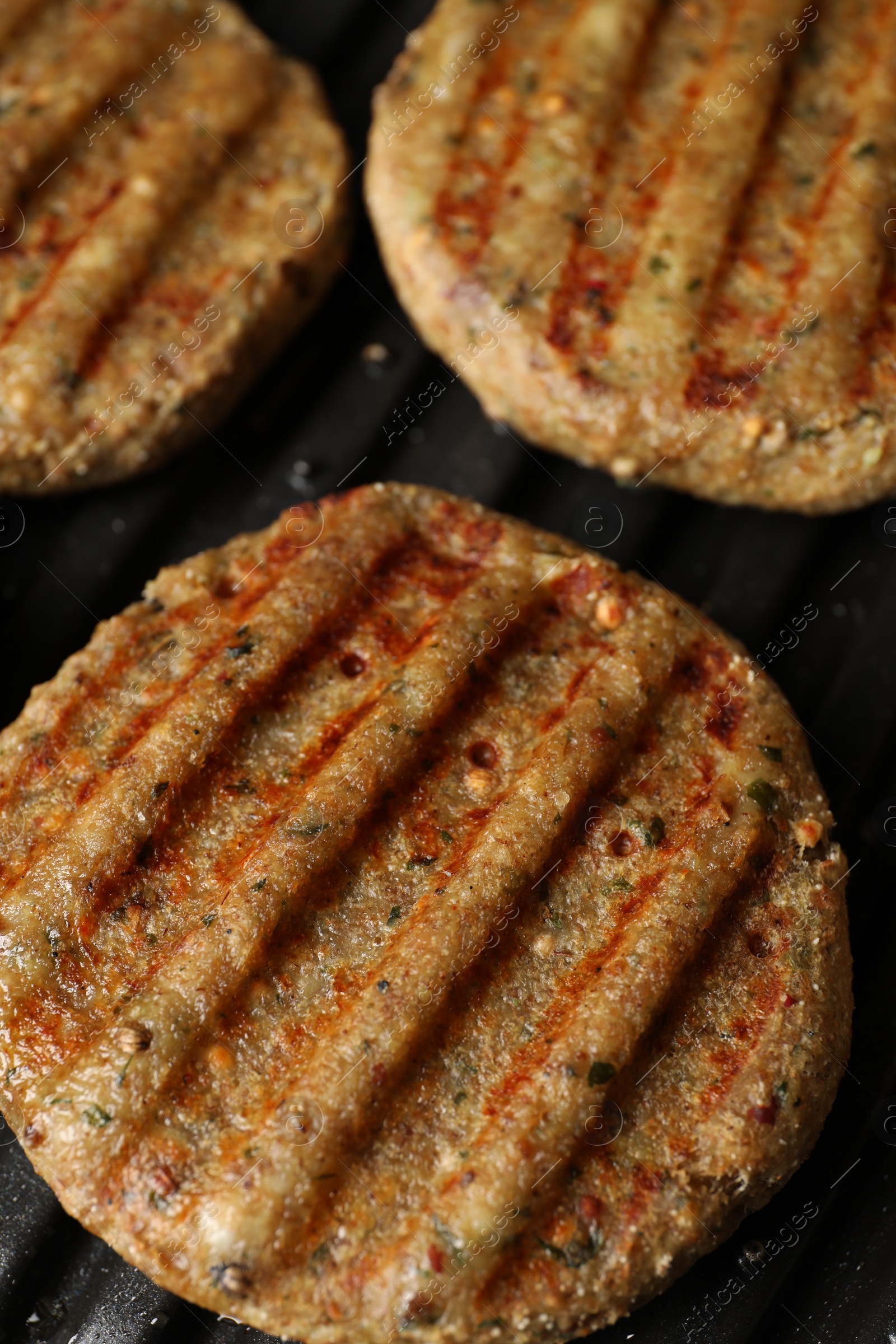 Photo of Delicious vegan cutlets cooking on electric grill, closeup