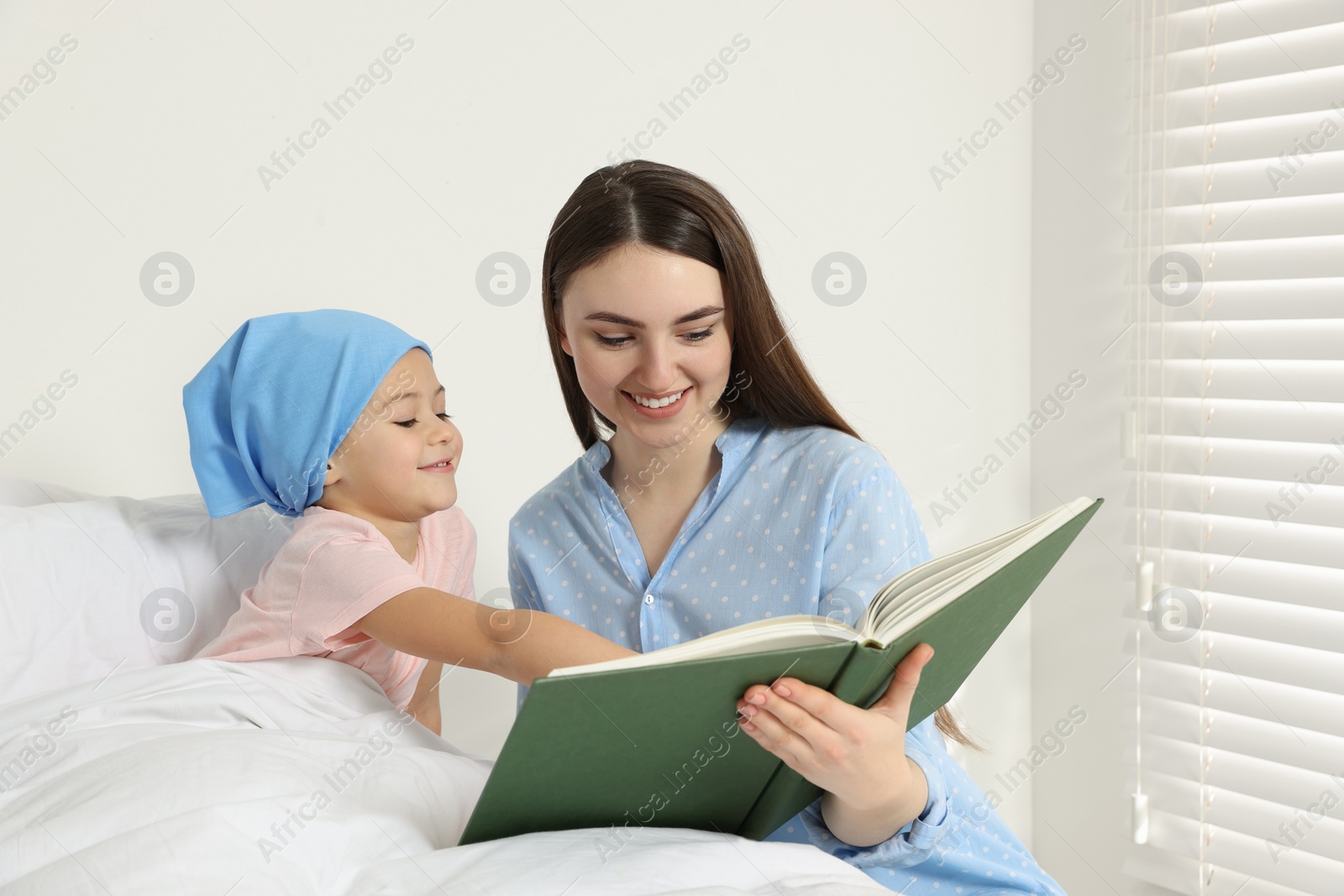 Photo of Childhood cancer. Mother and daughter reading book in hospital