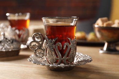 Glass of traditional Turkish tea in vintage holder on wooden table, closeup