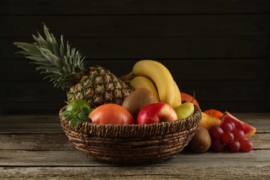 Fresh ripe fruits and wicker bowl on wooden table