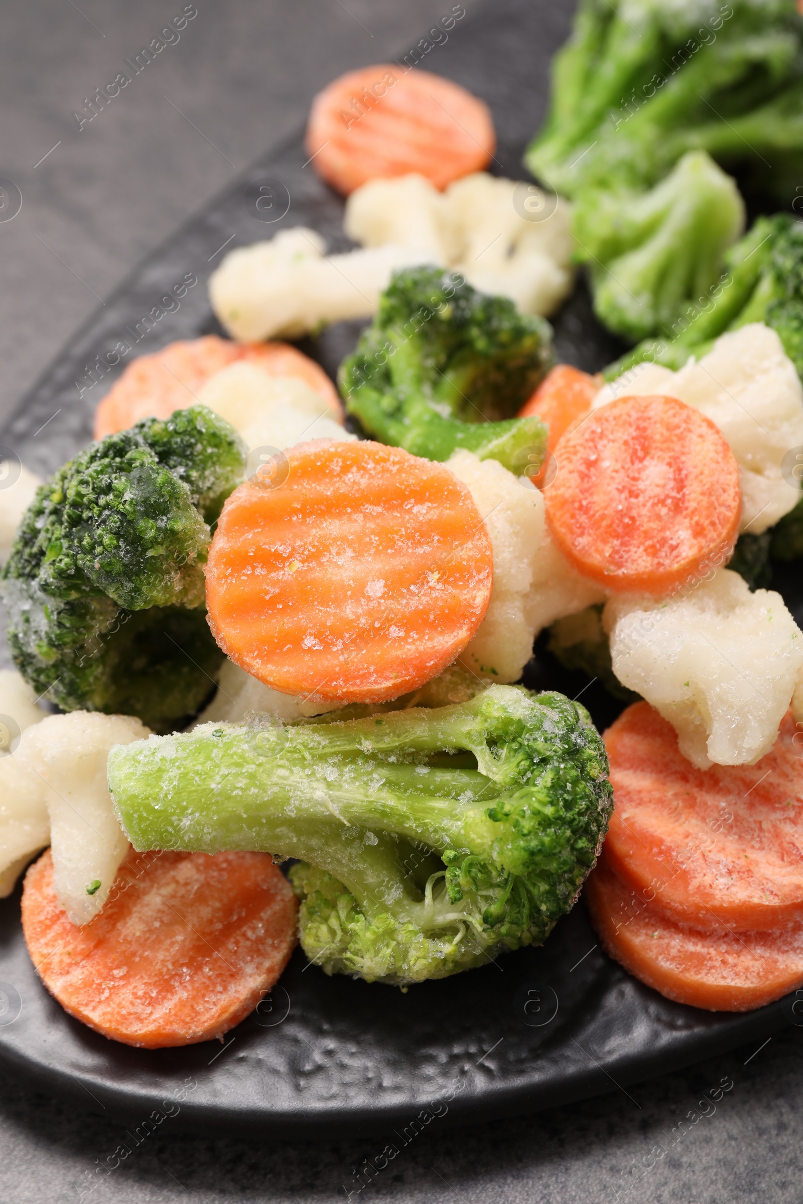 Photo of Mix of different frozen vegetables on grey table, closeup