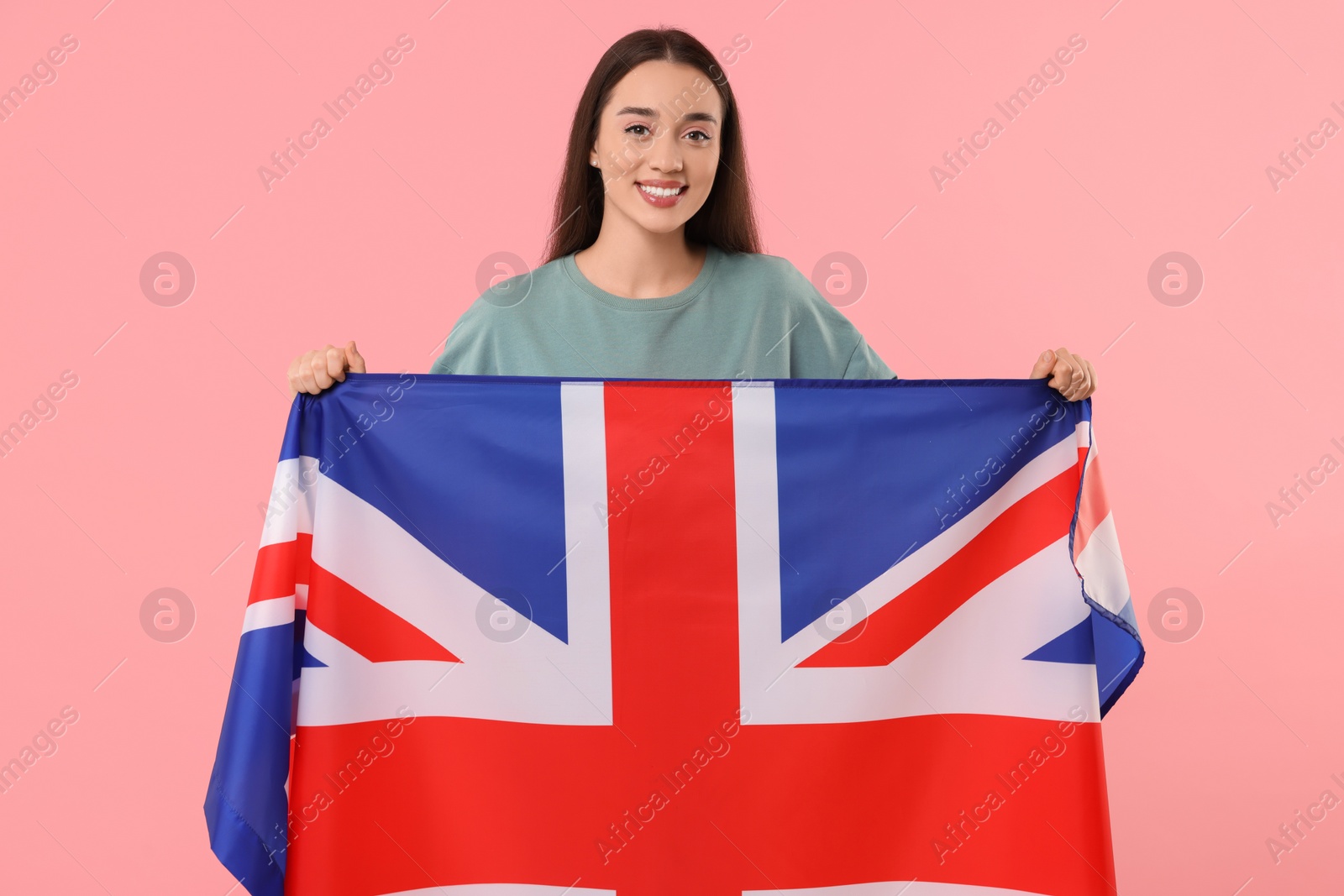 Photo of Young woman holding flag of United Kingdom on pink background