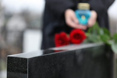 Photo of Black granite tombstone outdoors, closeup. Funeral ceremony