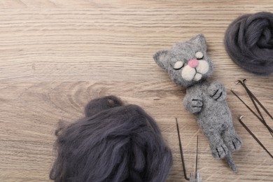 Photo of Felted cat, wool and tools on wooden table, flat lay. Space for text