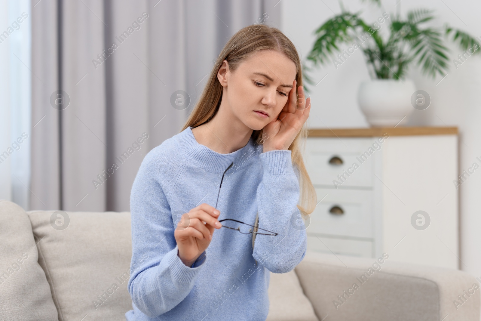 Photo of Overwhelmed young woman with glasses suffering from headache at home