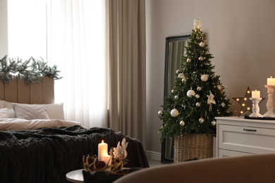 Photo of Beautiful decorated Christmas tree with fairy lights in bedroom interior